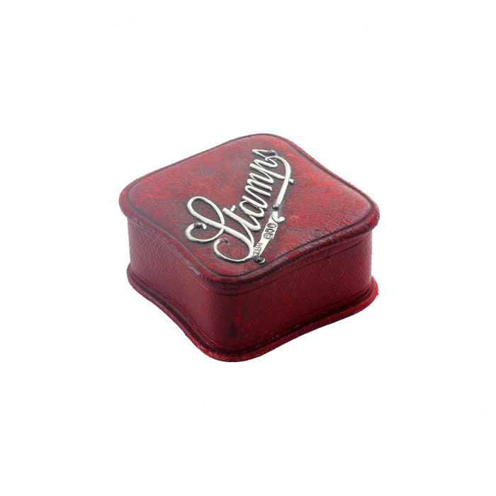a small red square stamp box with silver lettering